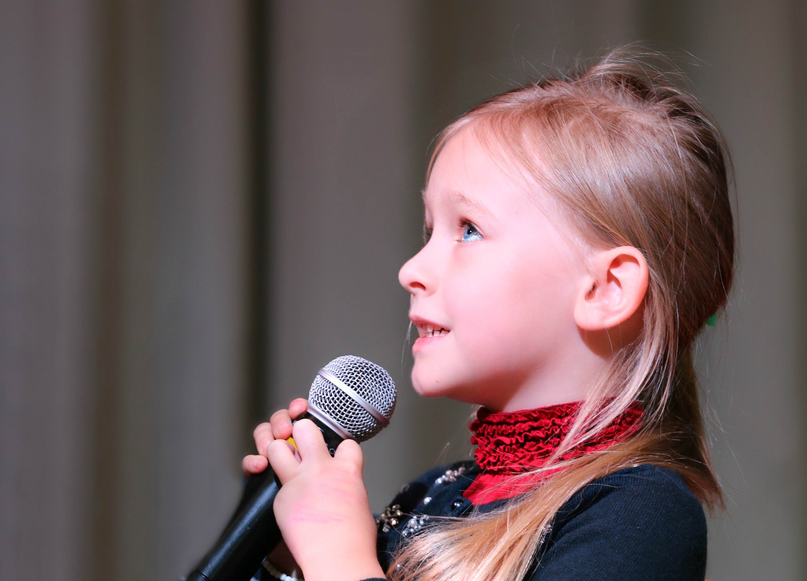 young blonde girl holding a microphone while taking voice lessons in Tampa