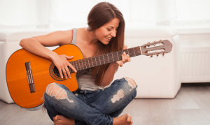 woman smiling while playing guitar
